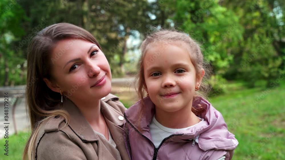 Portrait of mother and a small daughter, spends time together in a city park. Portrait of mother and a small daughter, spends time together in a city park.