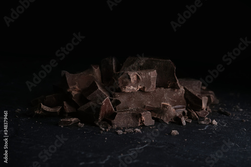 Pieces of tasty dark chocolate on black table