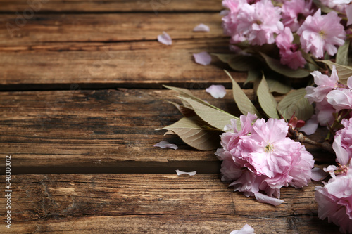 Sakura tree branch with beautiful blossom on wooden background, space for text. Japanese cherry