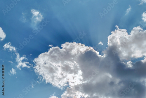 Beautiful blue sky with breaking rays of the sun due to white clouds.