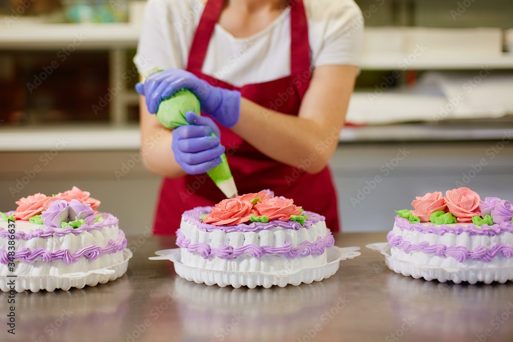 A pastry chef makes flowers from cream to decorate cakes.
