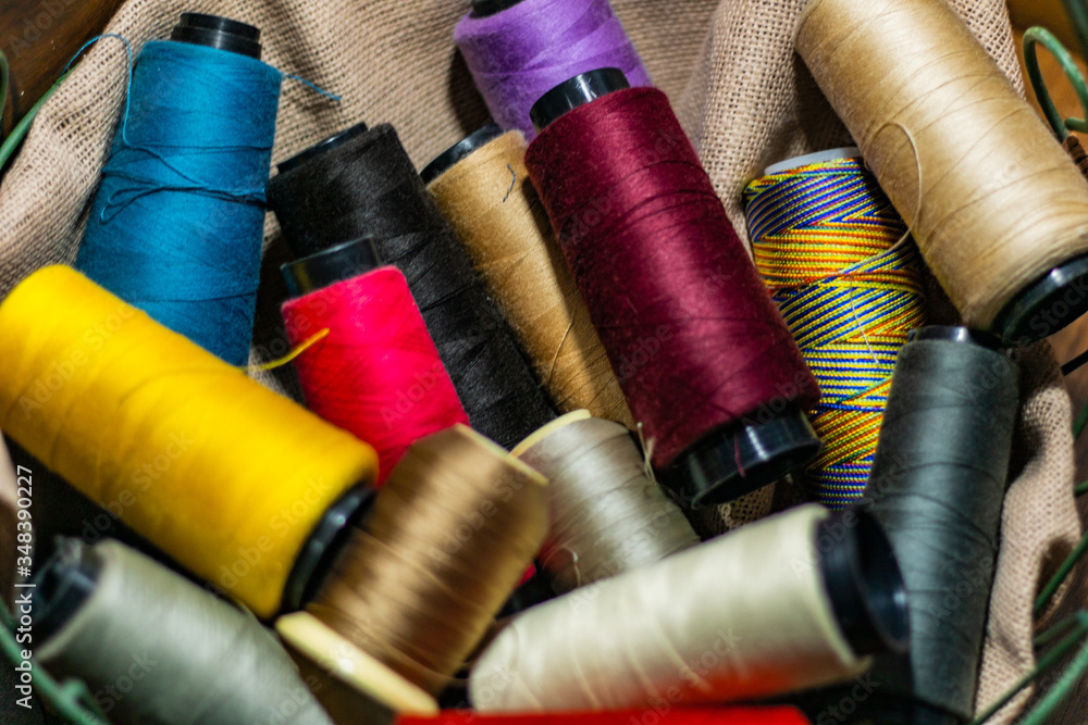 Various colors of thread rolls sits in wooden basket Various colors of thread rolls sits in wooden basket