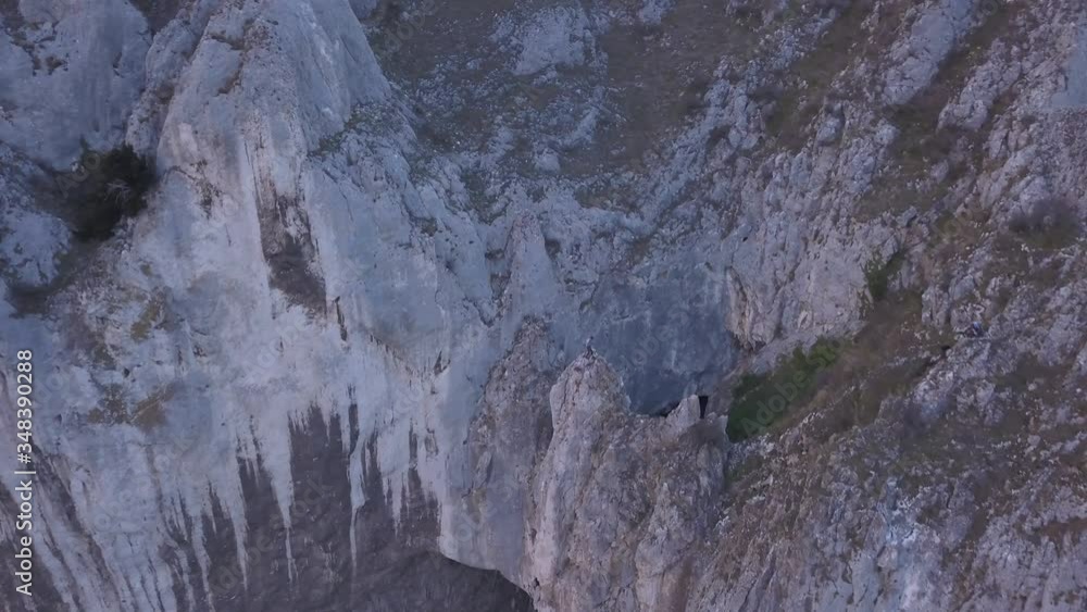 Aerial view from drone flying toward cliff and natural bridge arch feature. Via Ferrata, Sky Fly trail in Turda Gorge is a popular hiking and rock climbing destination of Europe to for enthusiasts. Aerial view from drone flying toward cliff and natural bridge arch feature. Via Ferrata, Sky Fly trail in Turda Gorge is a popular hiking and rock climbing destination of Europe to for enthusiasts.