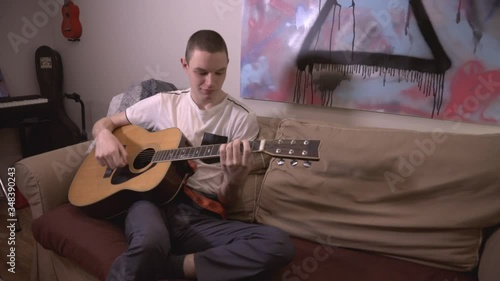 Young Man Comfortably Sitting On The Couch While Playing Guitar. - close up shot photo