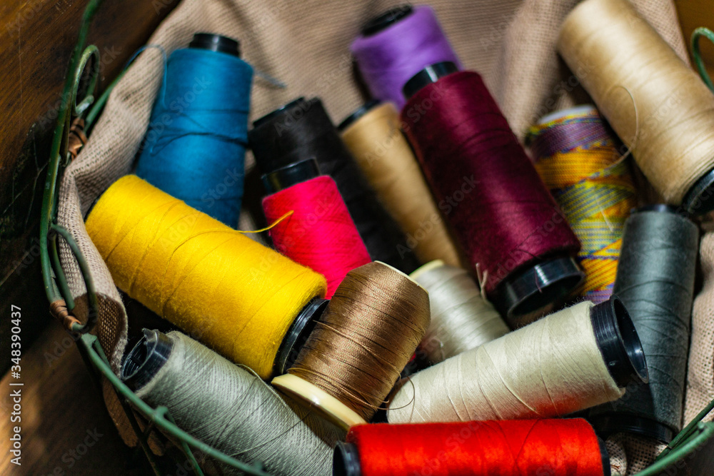 Various colors of thread rolls sits in wooden basket Various colors of thread rolls sits in wooden basket