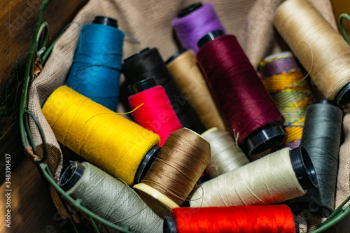 Various colors of thread rolls sits in wooden basket 