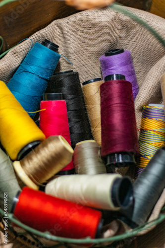 Various colors of thread rolls sits in wooden basket 