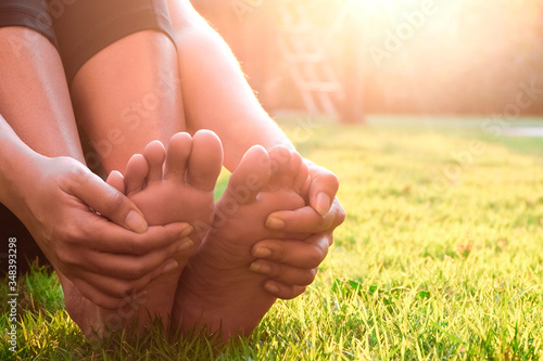 Foot pain .Woman sitting on grass Her hand caught at the foot. Having painful feet and stretching muscles fatigue To relieve pain. health concepts. © Photo Sesaon
