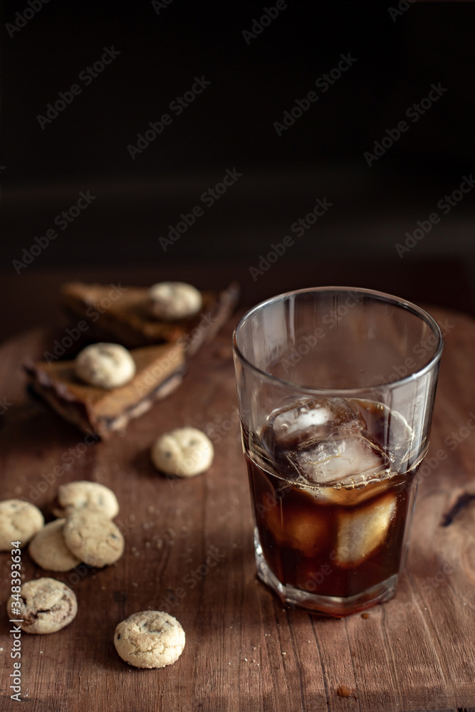 Transparent glass with cold coffee, sweets and cookies on a wooden table Transparent glass with cold coffee, sweets and cookies on a wooden table