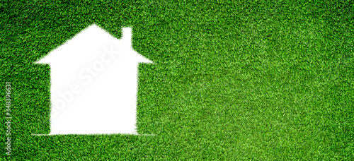 Home Ecology Concept : White home icon on green artificial grass field.