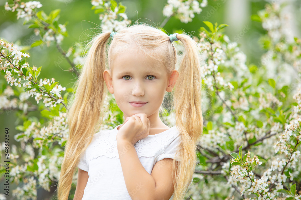 Small beautiful child girl portrait on the background of a flowering tree in spring Small beautiful child girl portrait on the background of a flowering tree in spring