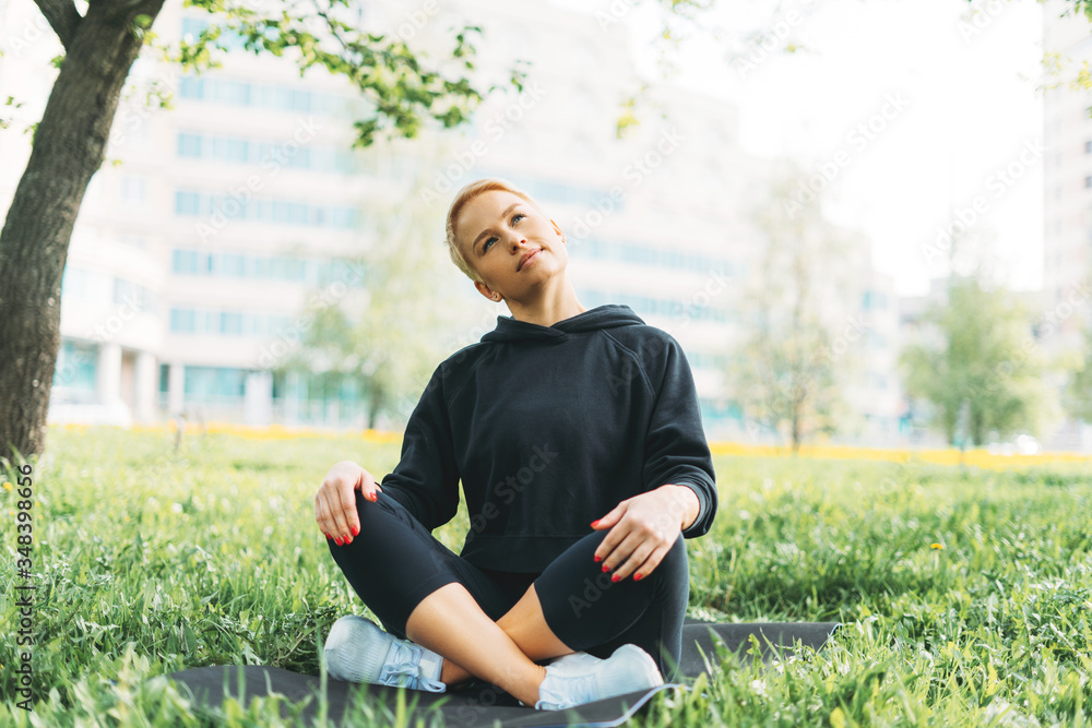 Attractive fit young woman in sport wear stretching on green grass in city park. Healthy lifestyle Attractive fit young woman in sport wear stretching on green grass in city park. Healthy lifestyle