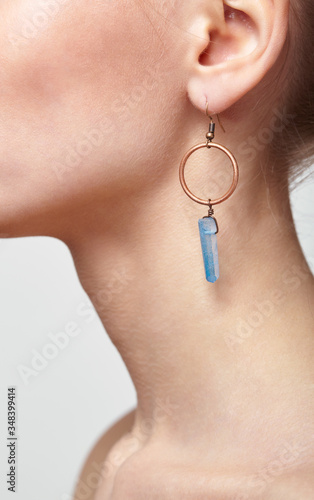 Foto Beautiful woman with galvanic earring in form of blue crystal