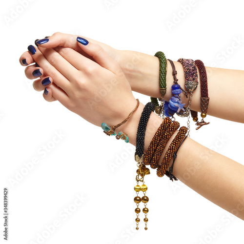 Female hands with handmaid bijouterie bracelets. Nails with blue manicure photo