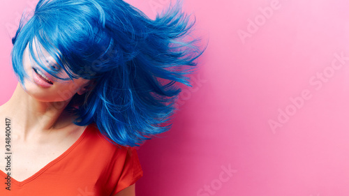 studio portrait of a sexy beautiful girl with a smile in motion on a pink background. Girl with blue hair photo