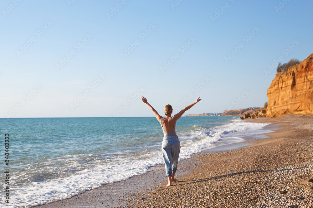 happy woman walks barefoot on the sand by the sea