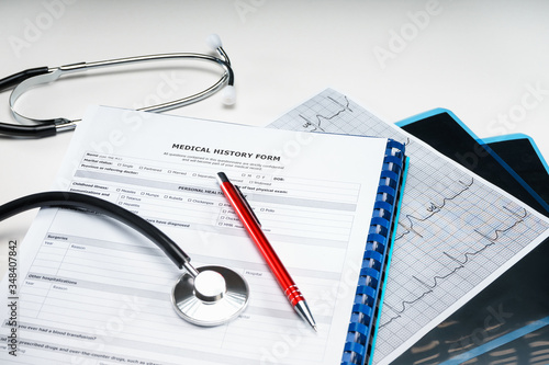 A stethoscope, cardiogram, pen and papers on doctor table or nurse desk. Medical concept.