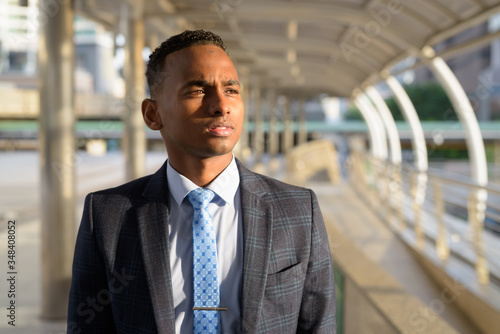 Young handsome African businessman wearing suit thinking in the city