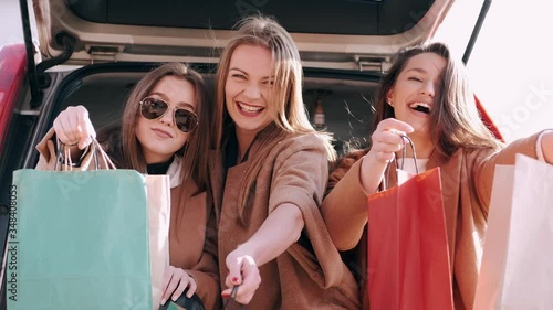 Three pretty girfriends are on shopping. Happy girls are checking the clothes they bought. photo