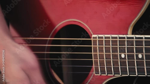 Close shot of a woman playing a red guitar outside.