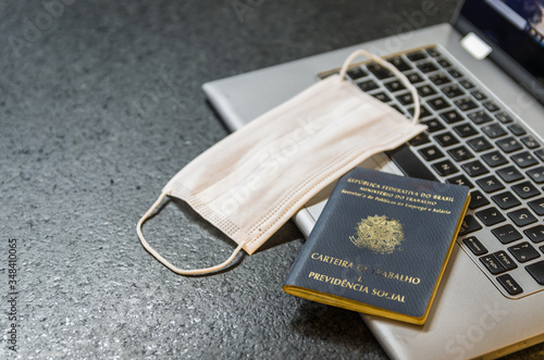 Tradução: República Federativa do Brasil, Ministério do Trabalho. / Carteira de Trabalho, laptop e máscara de proteção COVID-19 (coronavírus) photo