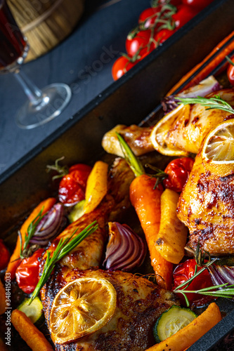 Grilled chicken legs with various vegetables and herbs.