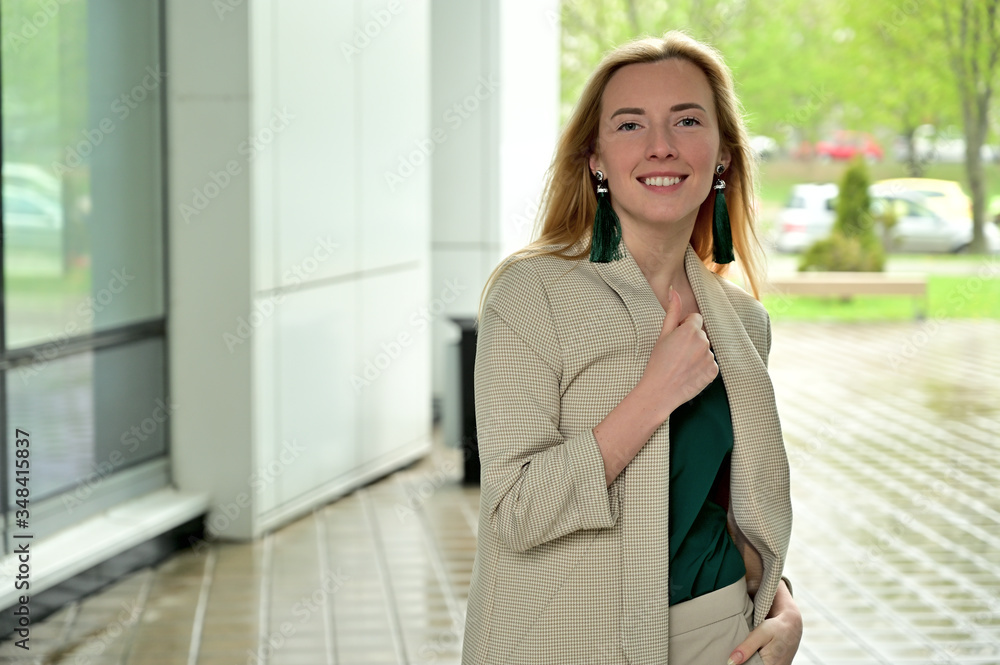 Photo portrait of a young business woman blonde smiling posing on a background of a city outdoors Photo portrait of a young business woman blonde smiling posing on a background of a city outdoors