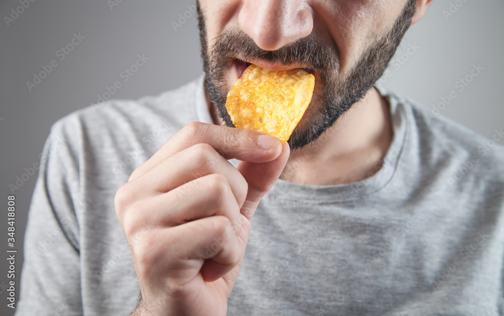Caucasian man eating tasty potato chips.