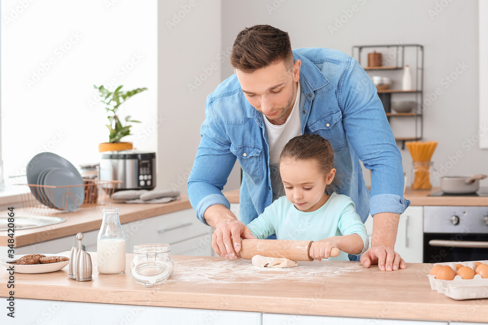 Happy father with little daughter making dough together in kitchen Happy father with little daughter making dough together in kitchen