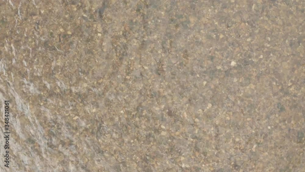 Top shot of a small river. Ground of the river visible, lots of pebbles on the ground. Camera flies slowly up. From close to wide shot. Aerial top down shot of a river. Top shot of a small river. Ground of the river visible, lots of pebbles on the ground. Camera flies slowly up. From close to wide shot. Aerial top down shot of a river.