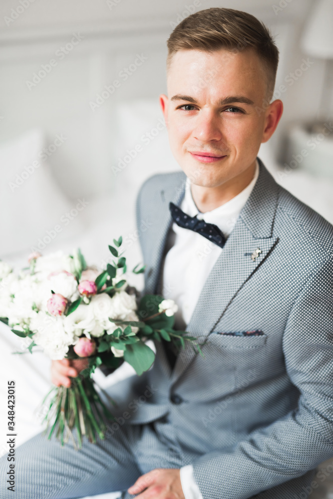 Happy handsome smiling groom posing with boutonniere Happy handsome smiling groom posing with boutonniere
