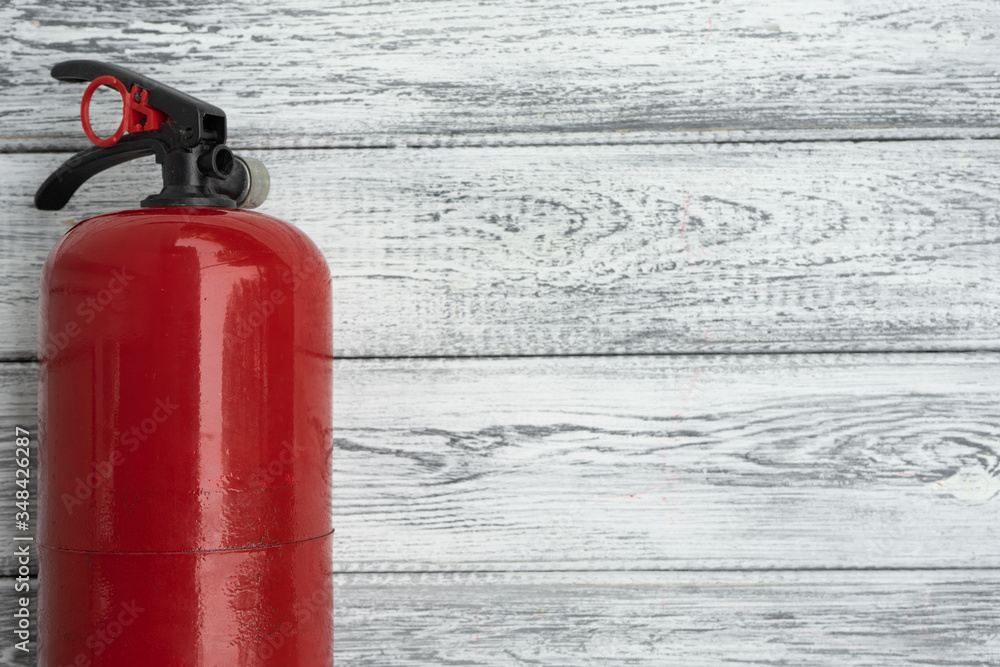 One red hand extinguishers on a light wooden background. Copy space. The concept of fire safety One red hand extinguishers on a light wooden background. Copy space. The concept of fire safety