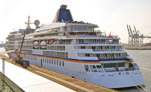 Luxury Hapag-Lloyd Cruises cruiseship yacht or cruise ship liner MS Europa  at Altona Cruise Terminal in port of Hamburg, Germany on sunny day with blue sky and containers and docks in background photo