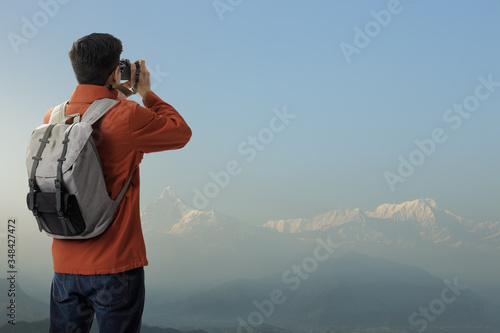 Hipster young asian man on the top of iceberg mountain with backpack in the nature and take a photo with digital camera the beauty of landscape, Adventure and travel in the mountains region concept