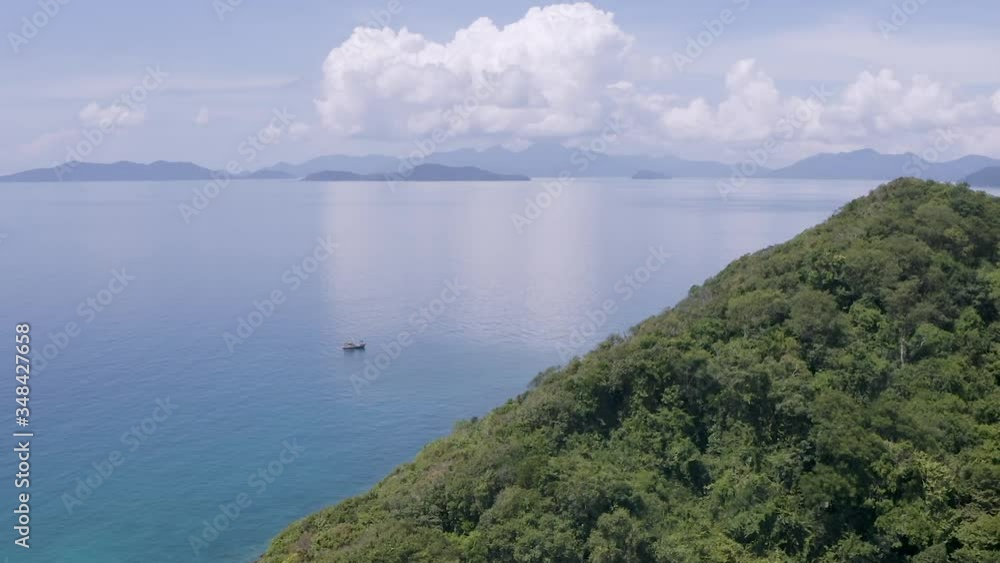 Rainforest island with fishing boat in the distance, AERIAL Rainforest island with fishing boat in the distance, AERIAL