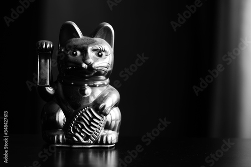 Maneki Neko, the Lucky Cat, covered with dust, black and white. Concept of fast passing time and expectation of good luck