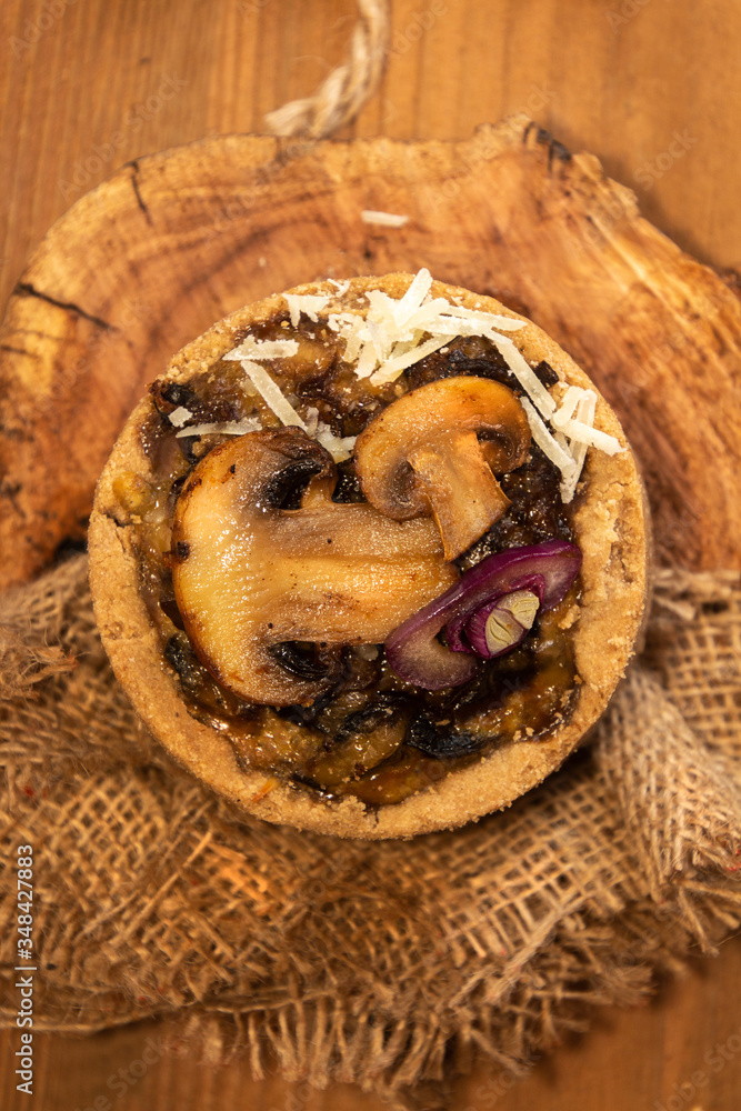 Tarts with mushrooms, caramelized red onion and cheese over on old wooden rustic background.