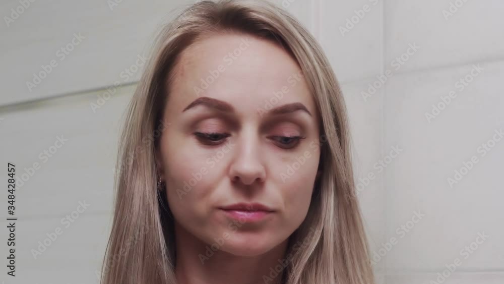 Woman applying lotion and looking at the camera Woman applying lotion and looking at the camera