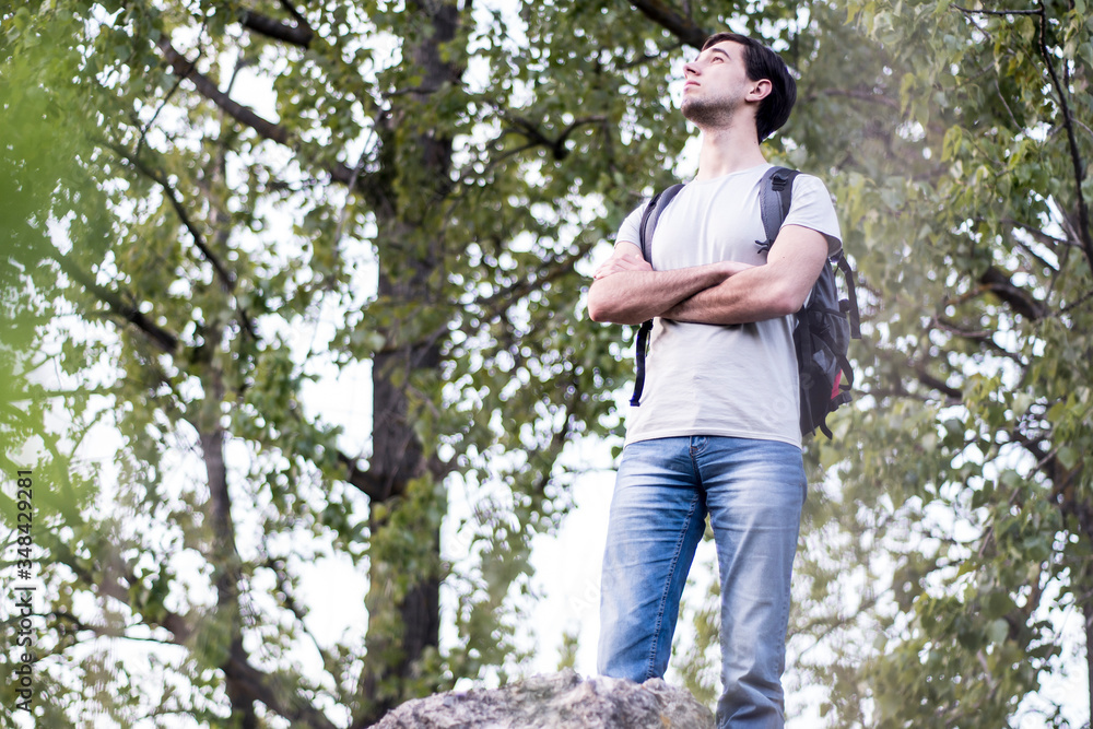 A young caucasian man standing in the nature, raising his head to the top and enjoying A young caucasian man standing in the nature, raising his head to the top and enjoying