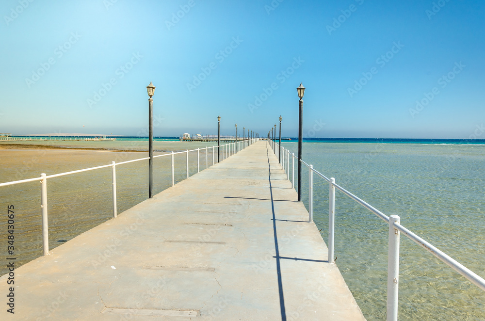 pier leading to the sea on a sunny day/empty pier overlooking the sea on a sunny day