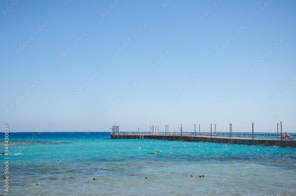 pier leading to the sea on a sunny day/empty pier overlooking the sea on a sunny day