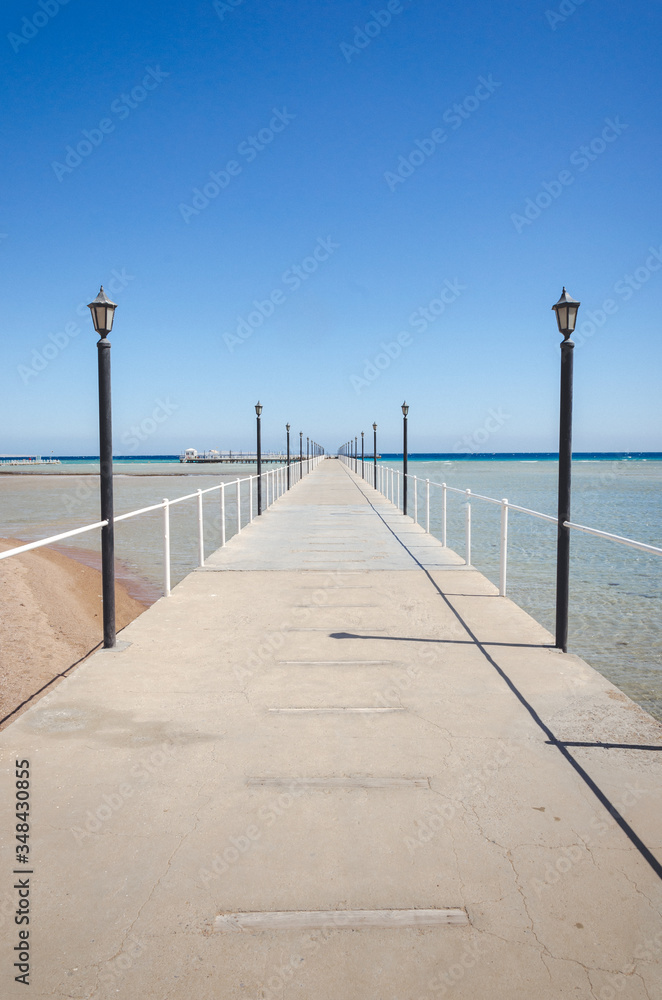 pier leading to the sea on a sunny day/empty pier overlooking the sea on a sunny day