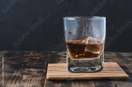 Glass of cognac with ice cubes on a wooden bar/Glass of cognac with ice cubes on a wooden bar on the background with copyspace