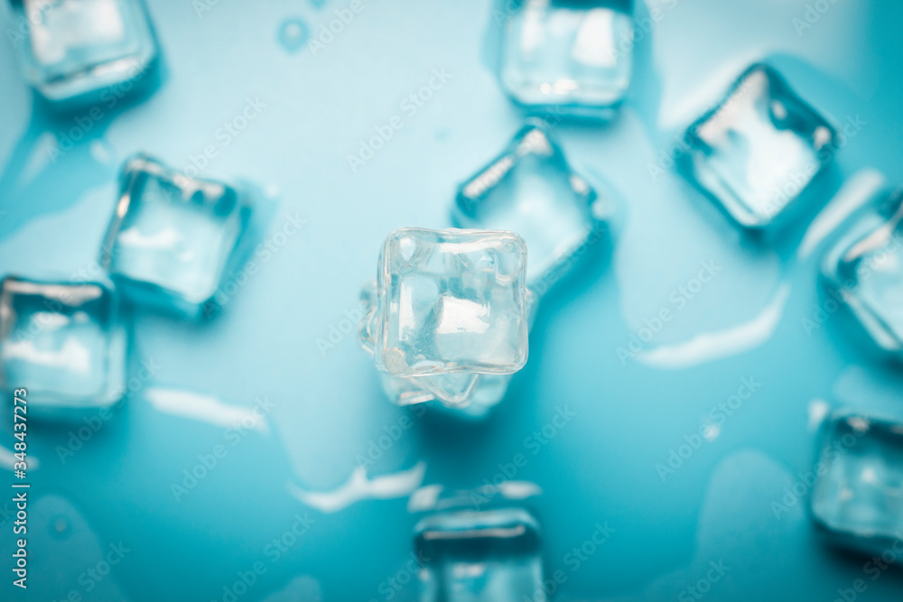 Ice cubes with water on a blue background. Ice concept for drinks. Banner. Flat lay, top view Ice cubes with water on a blue background. Ice concept for drinks. Banner. Flat lay, top view