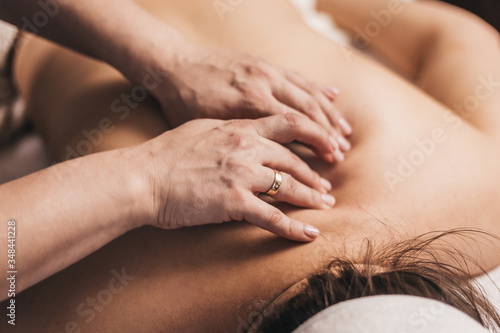 Treatment of pain in the spine with massage - hands of a masseur on the patient back - manual therapy