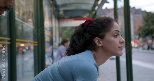 A young beautiful woman at the bus stop after workout.