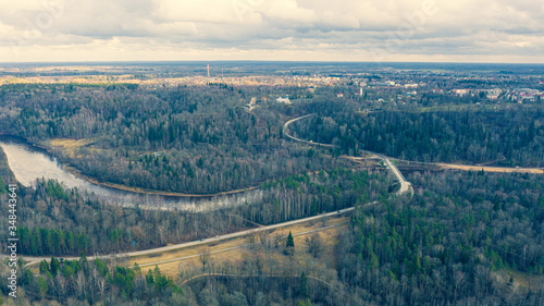Fototapeta Naklejka Na Ścianę i Meble -  Beautiful panoramic aerial view photo from flying drone over Sigulda city on a sunny winter day without snow against the background of forests and countryside. Sigulda, Latvia (series)