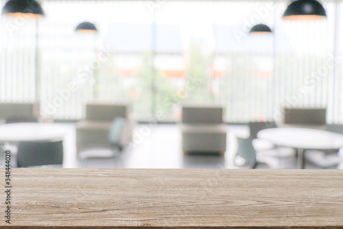 The empty wooden table surface for placing objects against a blurred white hallway background