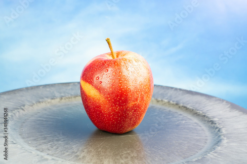 Fresh red apple fruit with water drops, blue sky background and copy space
