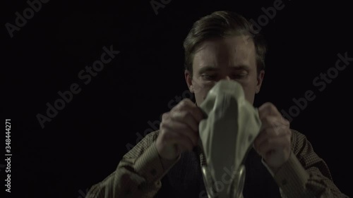 man in a suit on a black background puts on a gas mask. 4K video